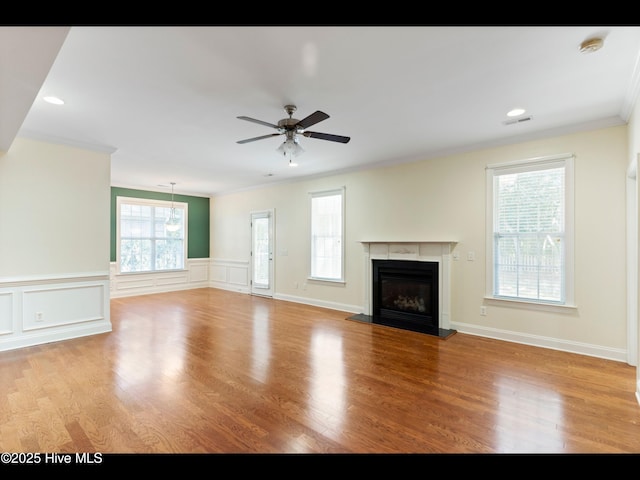 822 Lambrook Dr, Wilmington, NC 28411 - unfurnished living room with crown molding, ceiling fan, a glass covered fireplace, wood finished floors, and wainscoting