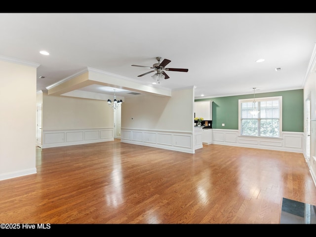 822 Lambrook Dr, Wilmington, NC 28411 - unfurnished living room featuring a chandelier, ceiling fan, ornamental molding, a decorative wall, and light wood-style flooring