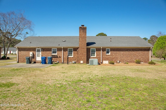 3007 Camelot Dr, Kinston, NC 28504 - back of house featuring central AC unit, a chimney, a yard, a patio, and brick siding