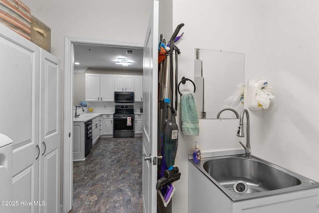 395 S Crow Creek Dr Unit 1511, Calabash, NC 28467 - kitchen featuring appliances with stainless steel finishes, a sink, white cabinets, and stone finish flooring