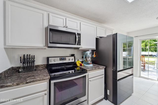 218 Yearling Loop, Jacksonville, NC 28540 - kitchen with appliances with stainless steel finishes, white cabinetry, a textured ceiling, light tile patterned flooring, and dark stone countertops