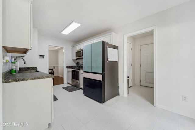 218 Yearling Loop, Jacksonville, NC 28540 - kitchen featuring stainless steel appliances, a sink, white cabinetry, dark countertops, and baseboards