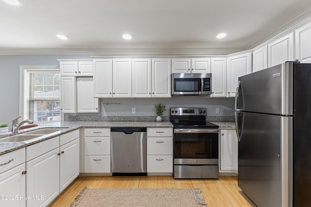 2415 Circle St, Wilmington, NC 28403 - kitchen with appliances with stainless steel finishes, a sink, white cabinets, light wood-type flooring, and crown molding