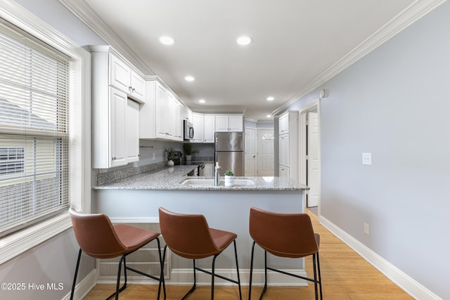 2415 Circle St, Wilmington, NC 28403 - kitchen featuring appliances with stainless steel finishes, crown molding, white cabinetry, a peninsula, and recessed lighting