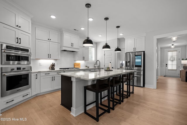 3625 Mason Port Dr, Wilmington, NC 28409 - kitchen with appliances with stainless steel finishes, light stone counters, a kitchen breakfast bar, white cabinets, and decorative backsplash
