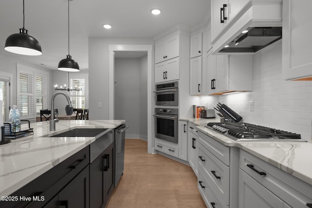 3625 Mason Port Dr, Wilmington, NC 28409 - kitchen with custom range hood, appliances with stainless steel finishes, white cabinets, a sink, and tasteful backsplash