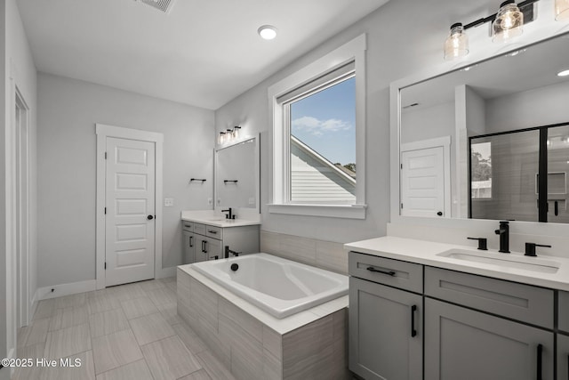 3625 Mason Port Dr, Wilmington, NC 28409 - full bathroom featuring two vanities, a garden tub, a shower stall, and baseboards