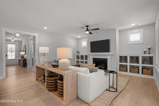 3625 Mason Port Dr, Wilmington, NC 28409 - living room featuring a glass covered fireplace, light wood-style floors, a ceiling fan, healthy amount of natural light, and recessed lighting