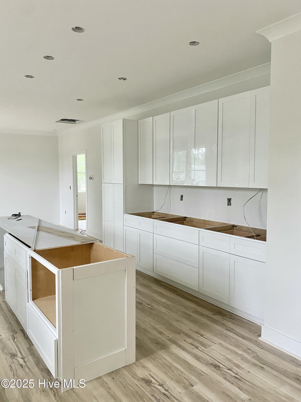 231 NE 77th St, Oak Island, NC 28465 - kitchen featuring light wood-style flooring, white cabinetry, and crown molding