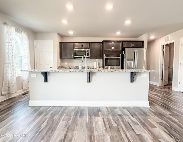126 Vick Ave, Carthage, NC 28327 - kitchen with appliances with stainless steel finishes, a breakfast bar area, an island with sink, dark brown cabinetry, and recessed lighting