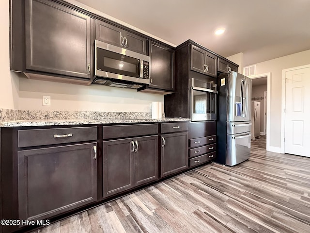 126 Vick Ave, Carthage, NC 28327 - kitchen featuring appliances with stainless steel finishes, light wood-style flooring, dark brown cabinets, light stone counters, and washing machine and dryer