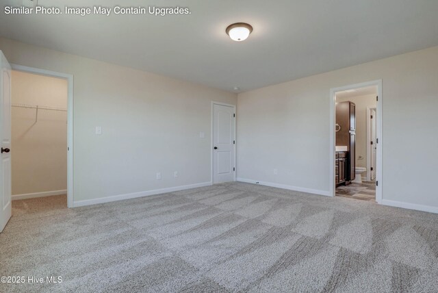 129 Tides End Dr Lot 34, Holly Ridge, NC 28445 - unfurnished bedroom featuring a walk in closet, carpet, baseboards, ensuite bathroom, and a closet