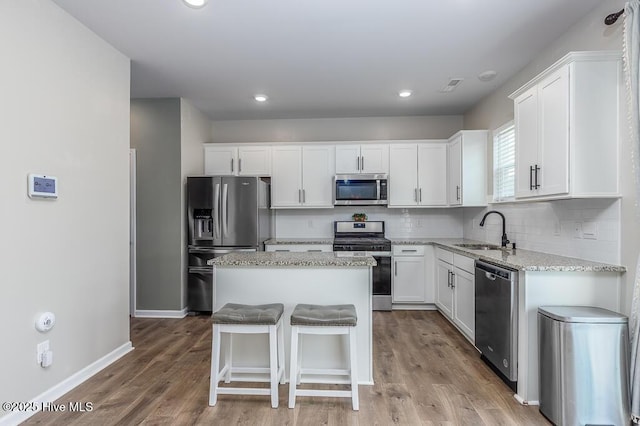 106 Featherstone Ln, New Bern, NC 28562 - kitchen featuring appliances with stainless steel finishes, a sink, a kitchen island, white cabinetry, and light stone countertops