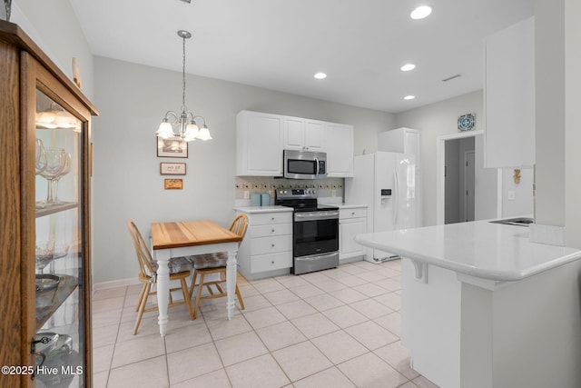 4156 Buckingham Ct, Southport, NC 28461 - kitchen featuring appliances with stainless steel finishes, white cabinetry, light tile patterned flooring, a chandelier, and recessed lighting