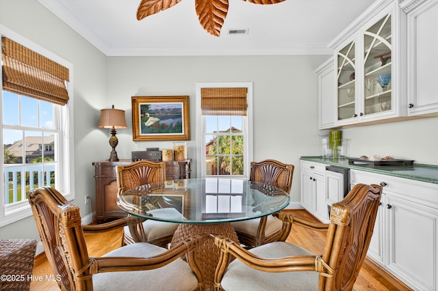 1510 N Shore Dr, Sunset Beach, NC 28468 - dining space with healthy amount of natural light, crown molding, a bar, and light wood finished floors