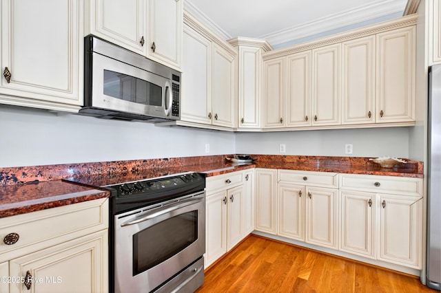 1510 N Shore Dr, Sunset Beach, NC 28468 - kitchen with appliances with stainless steel finishes, cream cabinetry, light wood-style floors, and dark stone counters