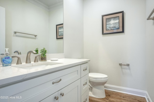 601 New River Inlet Rd, North Topsail Beach, NC 28460 - half bathroom featuring toilet, baseboards, wood finished floors, ornamental molding, and vanity