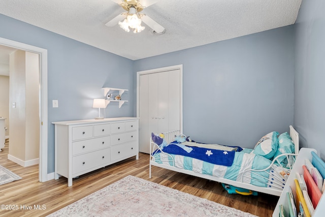 102 Oakwood Ln, Elizabeth City, NC 27909 - bedroom with light wood-style floors, a closet, a textured ceiling, baseboards, and a ceiling fan