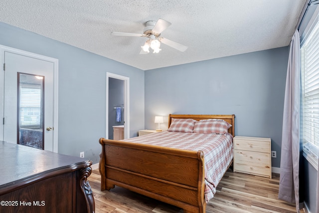 102 Oakwood Ln, Elizabeth City, NC 27909 - bedroom with light wood finished floors, a textured ceiling, baseboards, ceiling fan, and connected bathroom