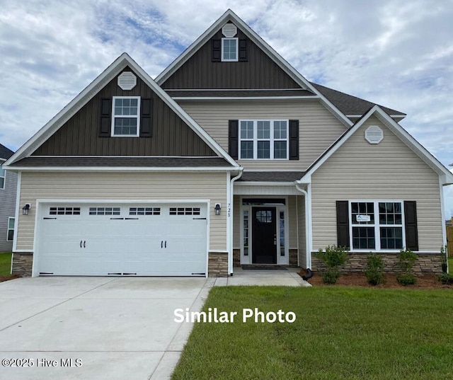 635 Indigo Johnston Dr, Jacksonville, NC 28546 - view of front facade with board and batten siding, stone siding, concrete driveway, a front yard, and an attached garage