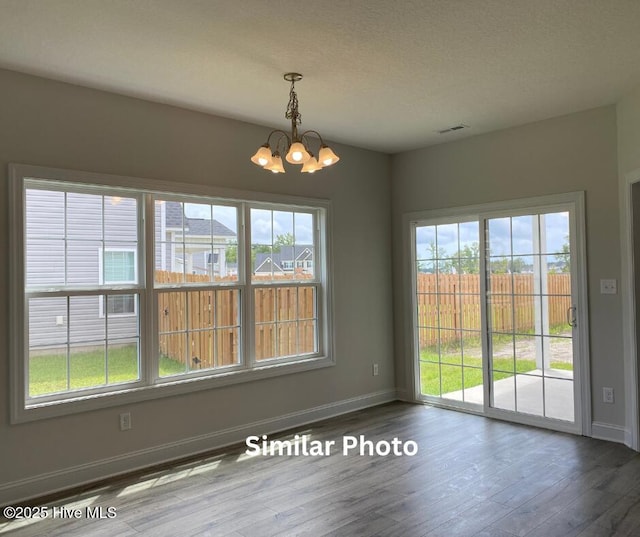 635 Indigo Johnston Dr, Jacksonville, NC 28546 - unfurnished dining area with a chandelier, wood finished floors, baseboards, healthy amount of natural light, and a textured ceiling