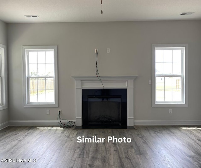 635 Indigo Johnston Dr, Jacksonville, NC 28546 - unfurnished living room featuring wood finished floors, a fireplace with flush hearth, healthy amount of natural light, and baseboards