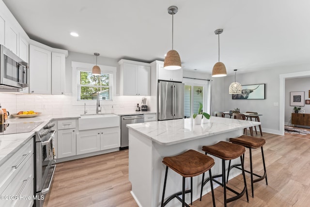 1015 E Moore St, Southport, NC 28461 - kitchen featuring stainless steel appliances, a sink, decorative backsplash, a kitchen island, and white cabinets
