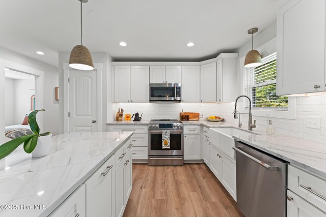 1015 E Moore St, Southport, NC 28461 - kitchen featuring appliances with stainless steel finishes, tasteful backsplash, a kitchen island, white cabinetry, and recessed lighting