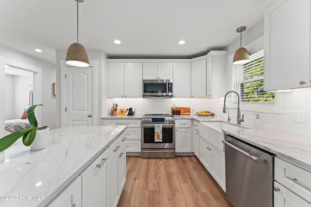 1015 E Moore St, Southport, NC 28461 - kitchen with stainless steel appliances, a sink, white cabinets, recessed lighting, and decorative backsplash