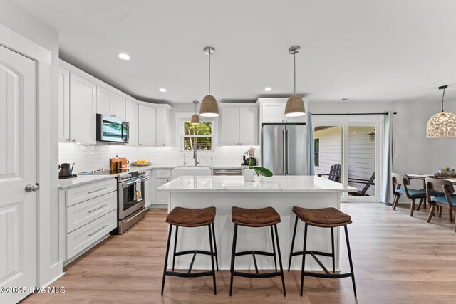 1015 E Moore St, Southport, NC 28461 - kitchen featuring stainless steel appliances, white cabinets, recessed lighting, backsplash, and light wood-style flooring