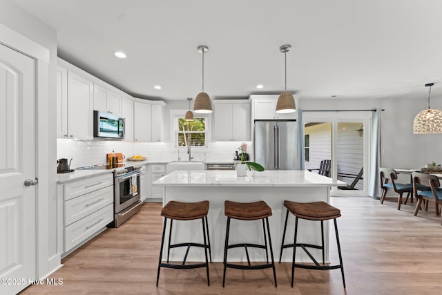 1015 E Moore St, Southport, NC 28461 - kitchen featuring stainless steel appliances, a breakfast bar area, a center island, tasteful backsplash, and white cabinetry