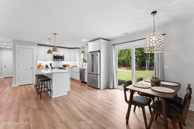 1015 E Moore St, Southport, NC 28461 - kitchen featuring stainless steel appliances, light countertops, backsplash, a sink, and light wood-type flooring