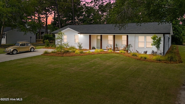 1015 E Moore St, Southport, NC 28461 - ranch-style house featuring covered porch, a lawn, concrete driveway, brick siding, and a shingled roof