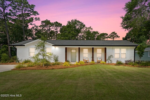 1015 E Moore St, Southport, NC 28461 - ranch-style house featuring covered porch, a front lawn, brick siding, and a shingled roof