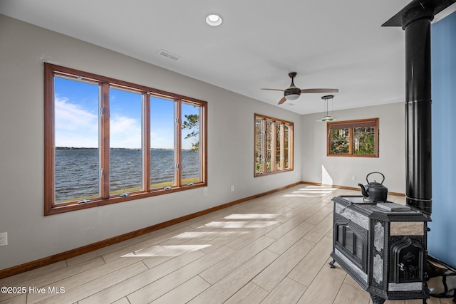 153 Windmill Point Dr, Vandemere, NC 28587 - living area featuring a wood stove, light wood-style floors, a water view, a ceiling fan, and baseboards