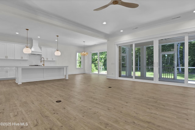 8241 Sage Valley Dr, Wilmington, NC 28411 - unfurnished living room featuring a ceiling fan, light wood finished floors, recessed lighting, baseboards, and a chandelier