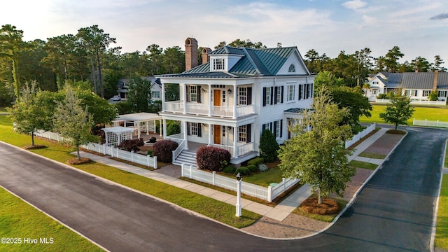 588 E Harborside Rd, Oriental, NC 28571 - greek revival inspired property featuring a porch, a balcony, a standing seam roof, a chimney, and metal roof