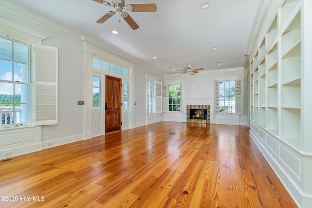 588 E Harborside Rd, Oriental, NC 28571 - unfurnished living room with a ceiling fan, ornamental molding, light wood-type flooring, a decorative wall, and a brick fireplace