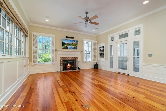 588 E Harborside Rd, Oriental, NC 28571 - unfurnished living room featuring a decorative wall, a ceiling fan, a fireplace, hardwood / wood-style floors, and crown molding