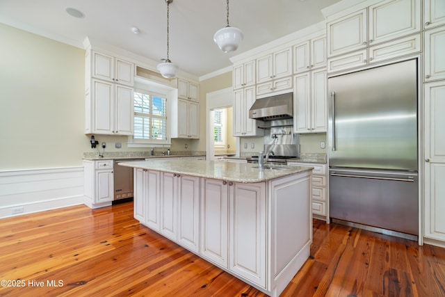 588 E Harborside Rd, Oriental, NC 28571 - kitchen with stainless steel appliances, under cabinet range hood, light wood-type flooring, a center island with sink, and light stone counters