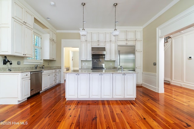 588 E Harborside Rd, Oriental, NC 28571 - kitchen with stainless steel appliances, hardwood / wood-style floors, a center island with sink, white cabinetry, and ornamental molding