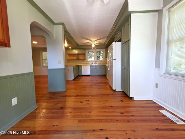 1700 Green Springs Rd, New Bern, NC 28560 - kitchen with a ceiling fan, white appliances, a wainscoted wall, arched walkways, and light wood finished floors