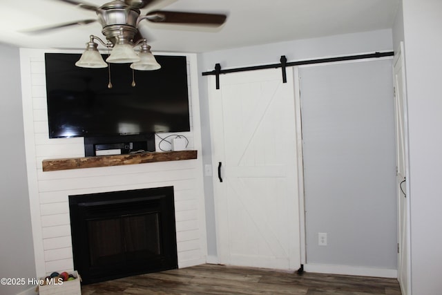 121 Pine Grove Rd, Newport, NC 28570 - unfurnished living room featuring ceiling fan, a barn door, wood finished floors, a large fireplace, and baseboards