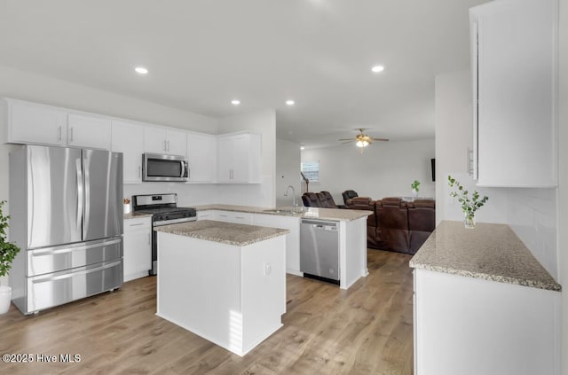 119 Perrytown Loop Rd, New Bern, NC 28562 - kitchen with appliances with stainless steel finishes, a peninsula, open floor plan, white cabinetry, and a kitchen island