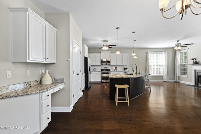 113 Percy Padgett Ct, Holly Ridge, NC 28445 - kitchen with stainless steel appliances, a ceiling fan, dark wood finished floors, white cabinetry, and a kitchen bar