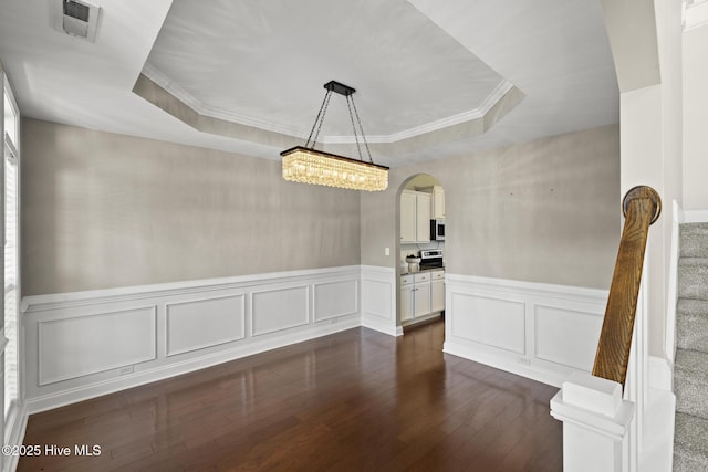 113 Percy Padgett Ct, Holly Ridge, NC 28445 - unfurnished dining area with a raised ceiling, arched walkways, dark wood-style floors, a wainscoted wall, and ornamental molding