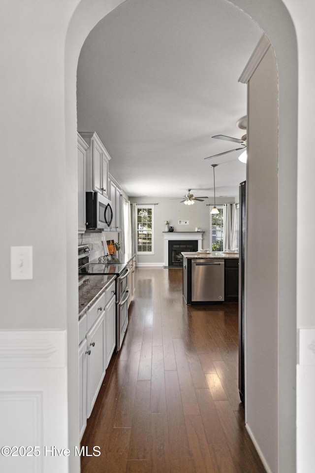 113 Percy Padgett Ct, Holly Ridge, NC 28445 - kitchen with appliances with stainless steel finishes, arched walkways, ceiling fan, open floor plan, and white cabinetry