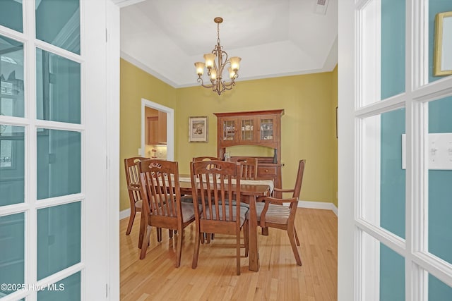 3878 White Blossom Cir, Southport, NC 28461 - dining area featuring a chandelier, light wood-style flooring, baseboards, and a raised ceiling