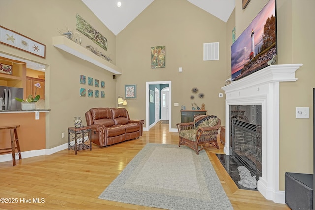 3878 White Blossom Cir, Southport, NC 28461 - living room with high vaulted ceiling, light wood finished floors, a fireplace with flush hearth, and baseboards