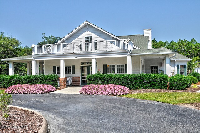 3878 White Blossom Cir, Southport, NC 28461 - view of front facade featuring a balcony, a chimney, and a porch